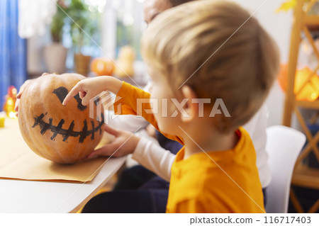 Child pointing at painted pumpkin face Child pointing at painted pumpkin face 116717403