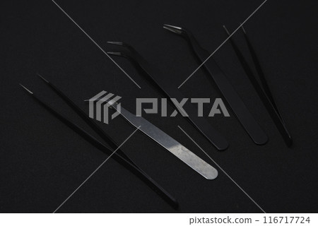 Metal tweezers for work. Tweezers for electronics on a black background. 116717724