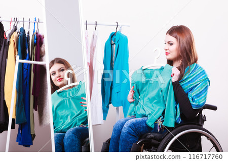 handicapped girl on wheelchair choosing clothes handicapped girl on wheelchair choosing clothes 116717760