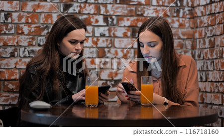 Two beautiful girls students have lunch in a city cafe and write a message 116718160