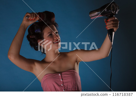 girl with curlers in hair holds hairdreyer 116718387