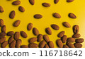 Vibrant close-up of scattered almonds on a bright yellow background 116718642