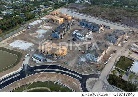 Aerial view of unfinished wooden frames of apartment buildings under construction. Development of residential housing in American suburbs. Real estate market in the USA Aerial view of unfinished wooden frames of apartment buildings under construction. Development of residential housing in American suburbs. Real estate market in the USA 116718846