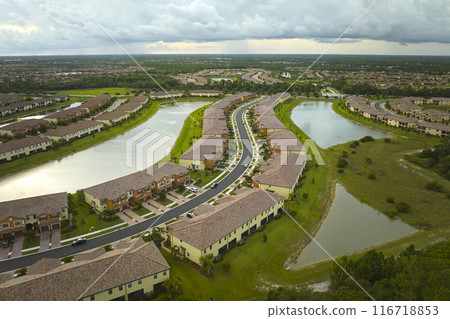 Aerial view of tightly packed homes in Florida closed living clubs with lake water in the middle. Family houses as example of real estate development in American suburbs Aerial view of tightly packed homes in Florida closed living clubs with lake water in the middle. Family houses as example of real estate development in American suburbs 116718853