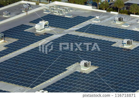 Aerial view of solar power plant with blue photovoltaic panels mounted on industrial building roof for producing green ecological electricity. Production of sustainable energy concept 116718871