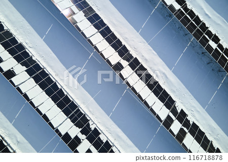 Aerial view of snow melting from covered solar photovoltaic panels at sustainable electric power plant for producing clean electrical energy. Low effectivity of renewable electricity in winter 116718878