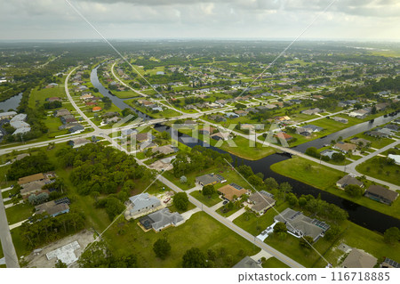Aerial view of small town America suburban landscape with private homes between green palm trees in Florida quiet residential area Aerial view of small town America suburban landscape with private homes between green palm trees in Florida quiet residential area 116718885