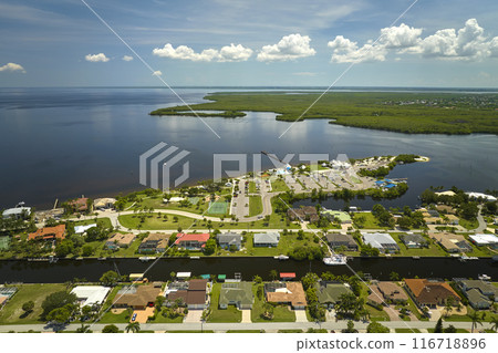 Aerial view of residential suburbs with private homes located on gulf coast near wildlife wetlands with green vegetation on sea shore. Living close to nature concept Aerial view of residential suburbs with private homes located on gulf coast near wildlife wetlands with green vegetation on sea shore. Living close to nature concept 116718896