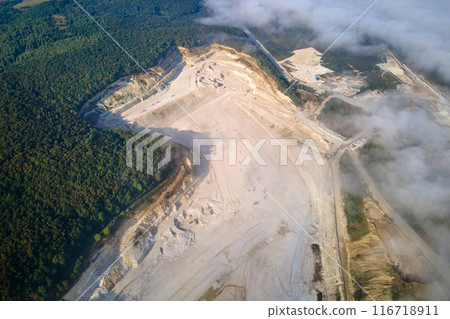 Aerial view of open pit mining of limestone materials for construction industry with excavators and dump trucks. 116718911
