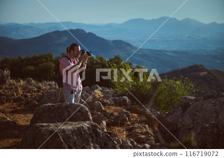 Man photographing scenic mountain landscape during hike in nature Man photographing scenic mountain landscape during hike in nature 116719072