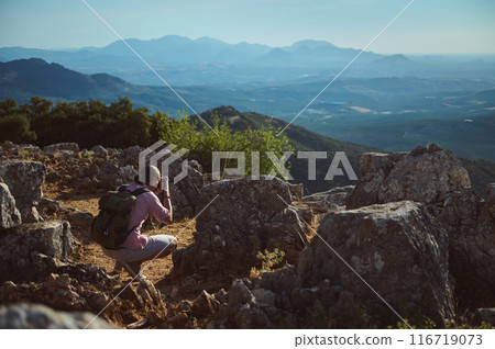 Photographer capturing nature in rocky mountain landscape during daytime with clear blue skies 116719073