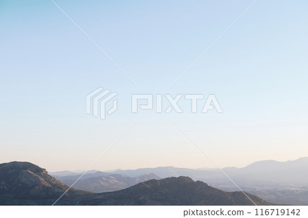 Serene mountain landscape during sunrise with clear blue sky and gentle slopes Serene mountain landscape during sunrise with clear blue sky and gentle slopes 116719142