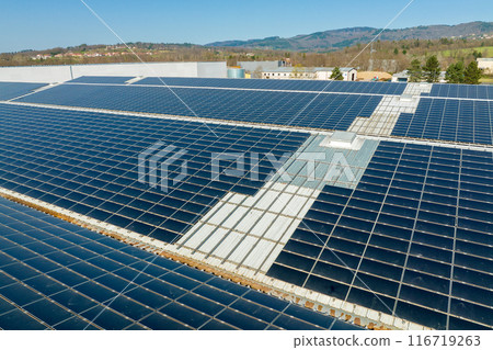 Aerial view of blue photovoltaic solar panels mounted on industrial building roof for producing green ecological electricity. Production of sustainable energy concept 116719263