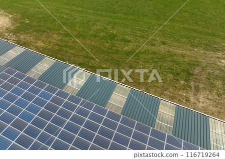 Aerial view of blue photovoltaic solar panels mounted on industrial building roof for producing green ecological electricity. Production of sustainable energy concept 116719264