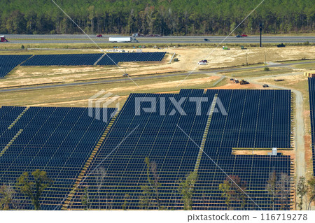 Aerial view of big sustainable electric power plant with many rows of solar photovoltaic panels for producing clean electrical energy. Renewable electricity with zero emission concept Aerial view of big sustainable electric power plant with many rows of solar photovoltaic panels for producing clean electrical energy. Renewable electricity with zero emission concept 116719278