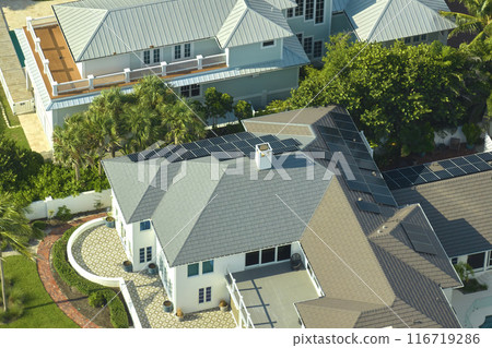 Aerial view of big expensive american building roof with blue solar photovoltaic panels for producing clean ecological electric energy. Investing in renewable electricity for retirement income concept Aerial view of big expensive american building roof with blue solar photovoltaic panels for producing clean ecological electric energy. Investing in renewable electricity for retirement income concept 116719286