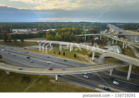 Aerial view of american freeway intersection with fast moving cars and trucks. USA transportation infrastructure concept Aerial view of american freeway intersection with fast moving cars and trucks. USA transportation infrastructure concept 116719291