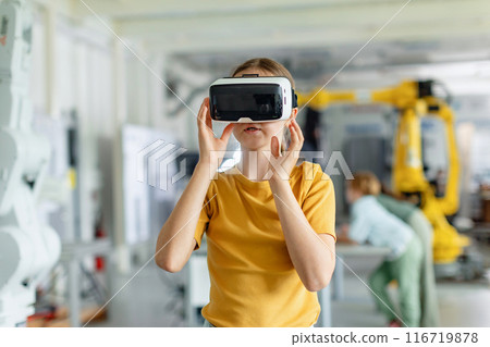 Portrait of schoolgirl with VR headset on head. Children learning robotics in Elementary school, using modern technology, virtual reality. Portrait of schoolgirl with VR headset on head. Children learning robotics in Elementary school, using modern technology, virtual reality. 116719878