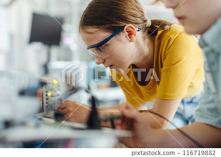 Two classmates working together on circuit board, building robot in after-school robotics club. Children learning robotics in Elementary school. 116719882