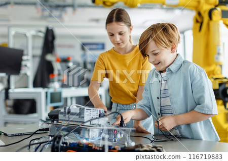 Two classmates working together on circuit board, building robot in after-school robotics club. Children learning robotics in Elementary school. Two classmates working together on circuit board, building robot in after-school robotics club. Children learning robotics in Elementary school. 116719883