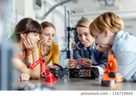 Children learning robotics in Elementary school. Young students building robot in after school robotics club. Field trip to real robotics laboratory. 116719884