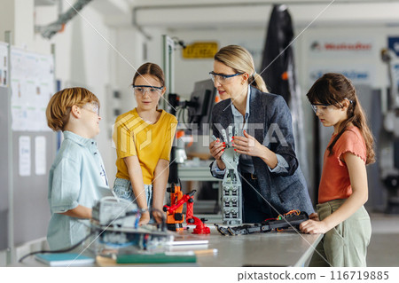 Children learning robotics in Elementary school. Young students building robot in after school robotics club. Field trip to real robotics laboratory. Children learning robotics in Elementary school. Young students building robot in after school robotics club. Field trip to real robotics laboratory. 116719885