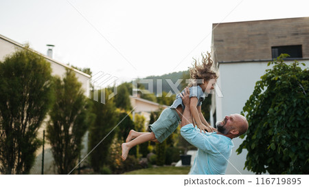 Father throwing little son up in the air in the garden. Dad with kid having fun outdoors. Father's day. 116719895
