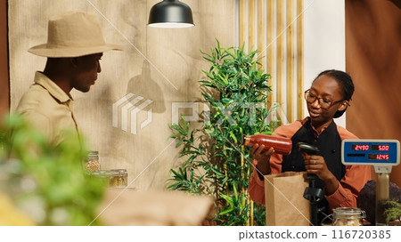 African american man paying for eco friendly food at checkout, using credit card on pos terminal for transaction. Adult supporting local farming and buying organic natural produce. Camera 1. African american man paying for eco friendly food at checkout, using credit card on pos terminal for transaction. Adult supporting local farming and buying organic natural produce. Camera 1. 116720385
