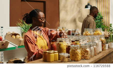 Vegan client examining types of pasta on sale at zero waste store, supporting local small business and low carbon footprint movement. Woman searching for natural eco friendly food supplies. Camera 1. Vegan client examining types of pasta on sale at zero waste store, supporting local small business and low carbon footprint movement. Woman searching for natural eco friendly food supplies. Camera 1. 116720388