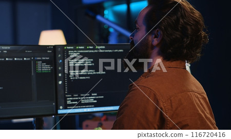 Smiling freelancing developer in home office doing coding on computer at desk. Cheerful IT expert doing contracted job from apartment, writing lines of code at workstation, camera A Smiling freelancing developer in home office doing coding on computer at desk. Cheerful IT expert doing contracted job from apartment, writing lines of code at workstation, camera A 116720416