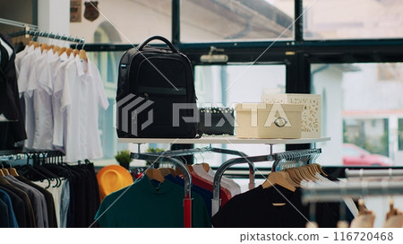 Empty fashion boutique selling new designer collection at shopping mall, having shoes and bags among clothes on stands. Interior of clothing store decorated with trendy tailoring items. Camera A. Empty fashion boutique selling new designer collection at shopping mall, having shoes and bags among clothes on stands. Interior of clothing store decorated with trendy tailoring items. Camera A. 116720468