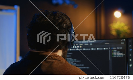 Technician putting headphones on while using coding to fortify firewalls, teleworking for IT company. Computer scientist listening music and upgrading binary code scripts in home office, camera A Technician putting headphones on while using coding to fortify firewalls, teleworking for IT company. Computer scientist listening music and upgrading binary code scripts in home office, camera A 116720476