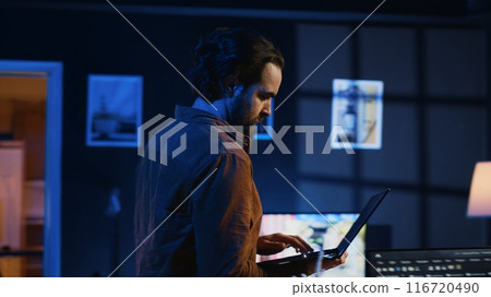 Man doing IT support job from home, walking around personal office with laptop in hand, coding. Nervous programmer wandering around room from stress, writing lines of code on notebook, camera A Man doing IT support job from home, walking around personal office with laptop in hand, coding. Nervous programmer wandering around room from stress, writing lines of code on notebook, camera A 116720490