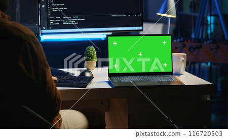 Green screen laptop next to freelancing man doing IT support job from apartment office, coding on PC. Mockup notebook on desk where software engineer writes lines of code on computer at home, camera A Green screen laptop next to freelancing man doing IT support job from apartment office, coding on PC. Mockup notebook on desk where software engineer writes lines of code on computer at home, camera A 116720503