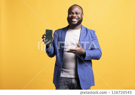 Cheerful african american man recommending green screen smartphone, isolated over studio background. Joyous BIPOC person presenting mockup mobile phone, giving positive feedback 116720545