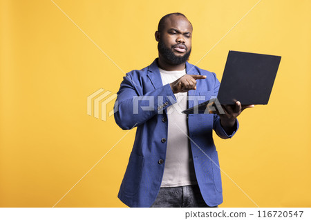 Irked man arguing with coworkers during videoconference meeting, studio background. Manager upset with employees performance, holding online video call to address situation Irked man arguing with coworkers during videoconference meeting, studio background. Manager upset with employees performance, holding online video call to address situation 116720547