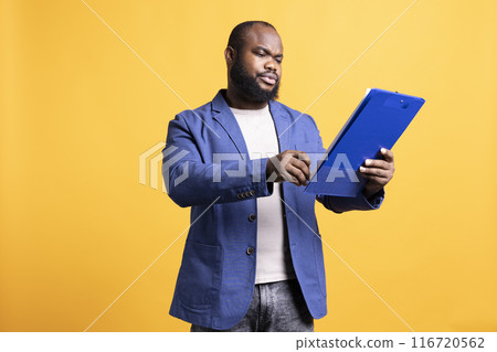 Man working accounting job browsing though financial report pages, studio background. Worker reading paperwork containing economic graphs and figures, solving bookkeeping tasks Man working accounting job browsing though financial report pages, studio background. Worker reading paperwork containing economic graphs and figures, solving bookkeeping tasks 116720562