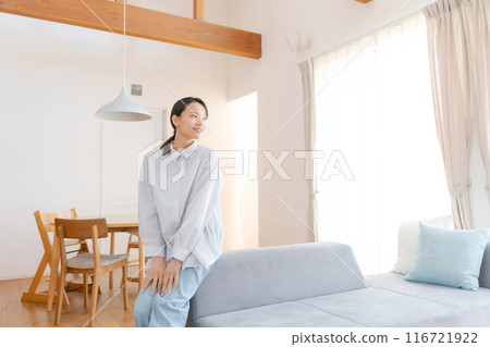 Woman sitting on sofa in living room 116721922