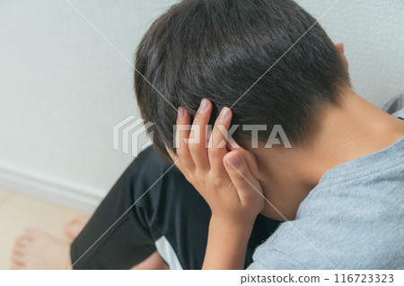 一個男孩用手摀住耳朵,低頭看 一個男孩用手摀住耳朵,低頭看 116723323