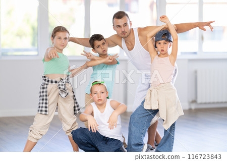 Happy group of young breakdancers artistically posing with male choreographer in bright hall Happy group of young breakdancers artistically posing with male choreographer in bright hall 116723843