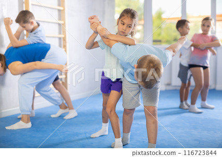 Kids in sportswear exercising self-protection techniques in pair during class 116723844
