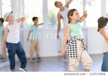 In sports studio, childrens team learns hip-hop dance accompanied by experienced man teacher In sports studio, childrens team learns hip-hop dance accompanied by experienced man teacher 116723908