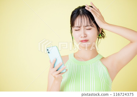 Lifestyle: A young woman looking at her smartphone in distress 116724375