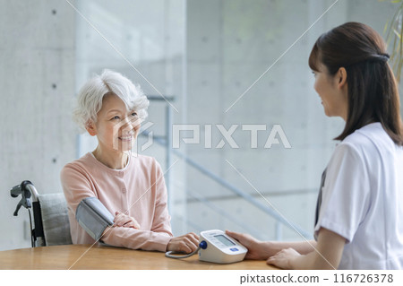 Senior woman having her blood pressure measured by a nurse 116726378