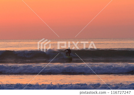A surfer riding the waves at Okuragahama Beach in Miyazaki during a beautiful sunrise 116727247