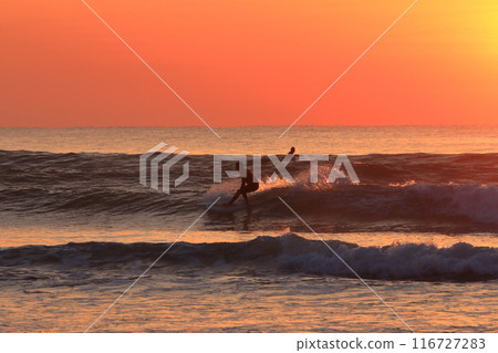 A person surfing in the ocean at Okuragahama Beach in Miyazaki Prefecture during a beautiful sunrise 116727283