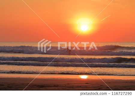A surfer riding the waves at Okuragahama Beach in Miyazaki Prefecture as the morning sun shines 116727290