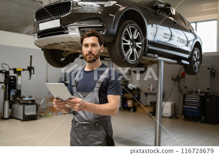 Mechanic using tablet for car inspection in modern workshop 116728679