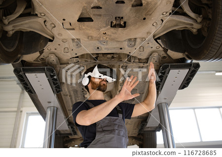 Mechanic using virtual glasses to inspect car on lift Mechanic using virtual glasses to inspect car on lift 116728685
