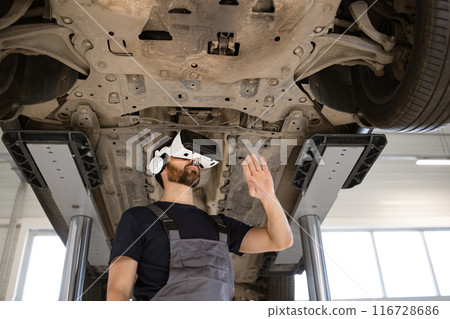 Mechanic using virtual reality glasses to examine car on lift 116728686